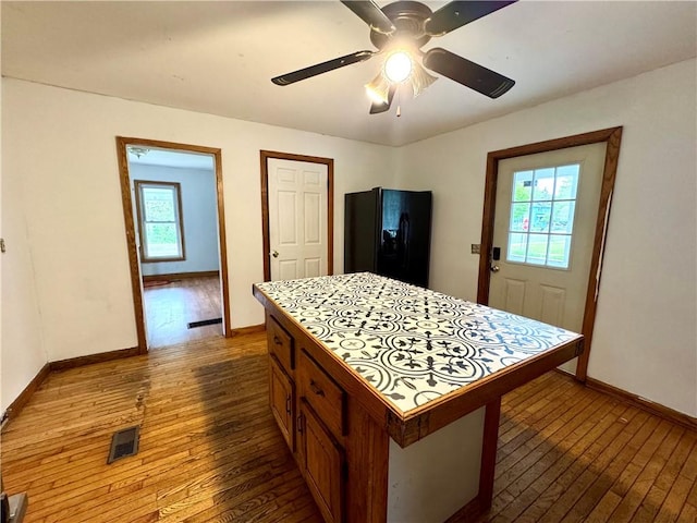 kitchen with black fridge, dark wood finished floors, baseboards, a ceiling fan, and tile countertops