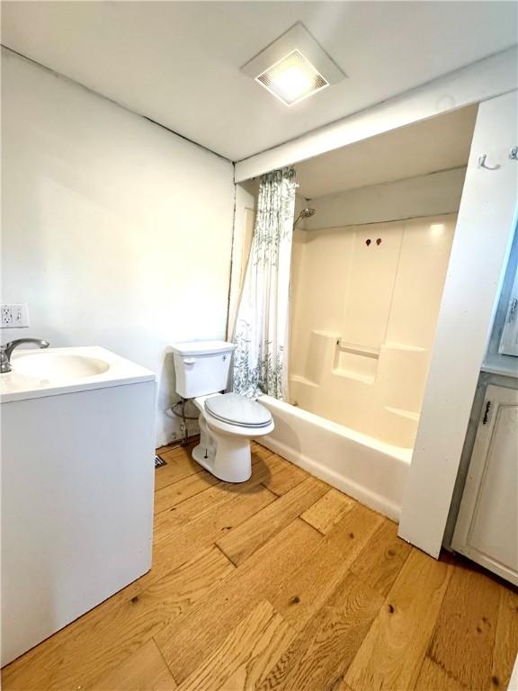 full bath featuring wood finished floors, toilet, shower / bath combination with curtain, and vanity