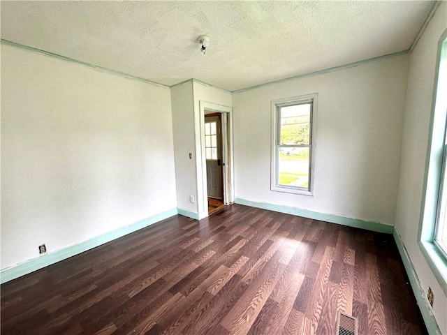 unfurnished room with dark wood-style flooring, a textured ceiling, and baseboards