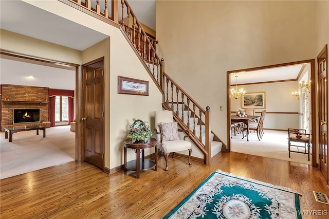 entryway featuring wood finished floors, stairs, a chandelier, a towering ceiling, and baseboards