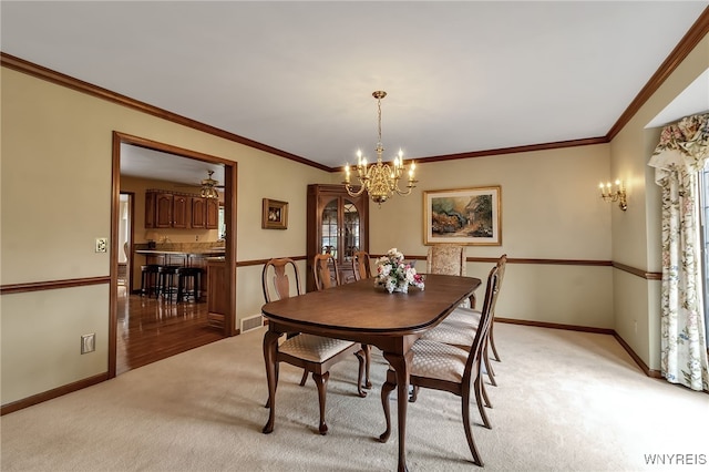dining room with a chandelier, light colored carpet, baseboards, and ornamental molding