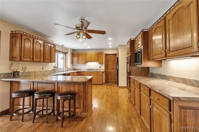 kitchen featuring a peninsula, built in microwave, brown cabinetry, a ceiling fan, and freestanding refrigerator
