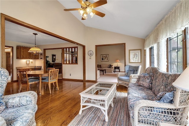 living area with lofted ceiling, wood finished floors, a ceiling fan, and baseboards