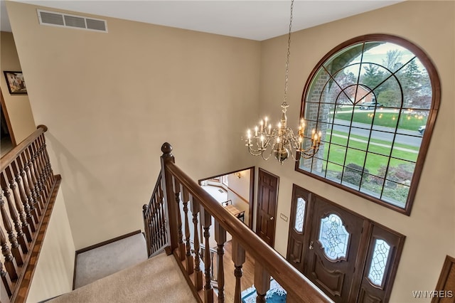 carpeted foyer entrance with a towering ceiling, a chandelier, and baseboards