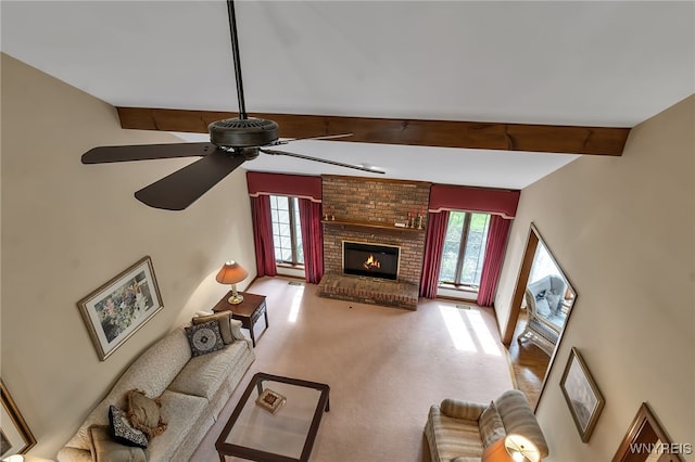 carpeted living area with beam ceiling, healthy amount of natural light, a ceiling fan, and a brick fireplace