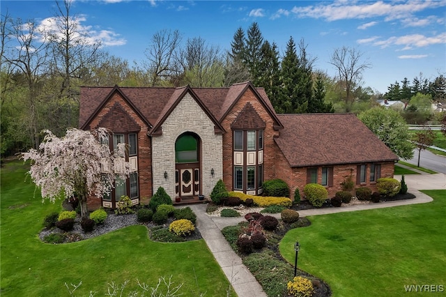 view of front of home featuring a front lawn, stone siding, and brick siding