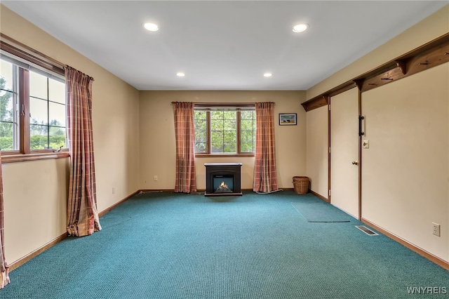 unfurnished living room with recessed lighting, carpet flooring, baseboards, and a lit fireplace