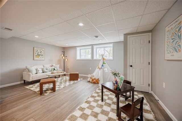 living room with a drop ceiling, light wood-type flooring, baseboards, and recessed lighting