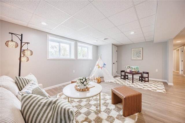 living room with light wood-style flooring, a paneled ceiling, recessed lighting, and baseboards