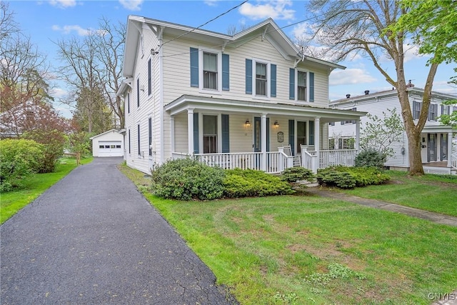 view of front of home featuring covered porch, a detached garage, and a front lawn