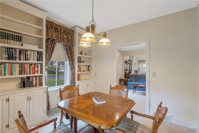 carpeted dining area featuring baseboards