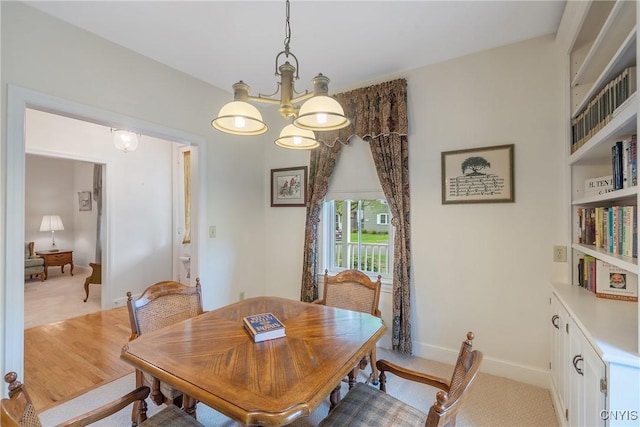 dining area with a chandelier, wood finished floors, and baseboards