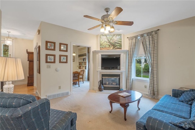carpeted living area featuring a fireplace with flush hearth, ceiling fan, and baseboards