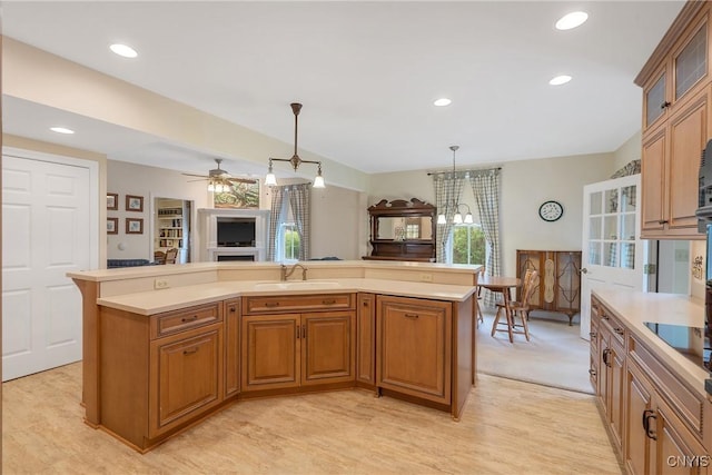 kitchen with light countertops, hanging light fixtures, glass insert cabinets, brown cabinetry, and recessed lighting