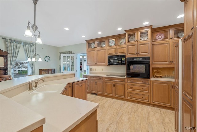 kitchen featuring black appliances, a sink, light countertops, recessed lighting, and hanging light fixtures