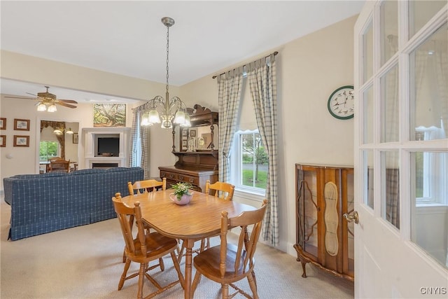 dining room with light carpet, healthy amount of natural light, a chandelier, and a ceiling fan