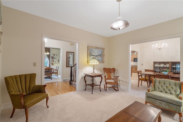 living area with light colored carpet, a chandelier, baseboards, and arched walkways