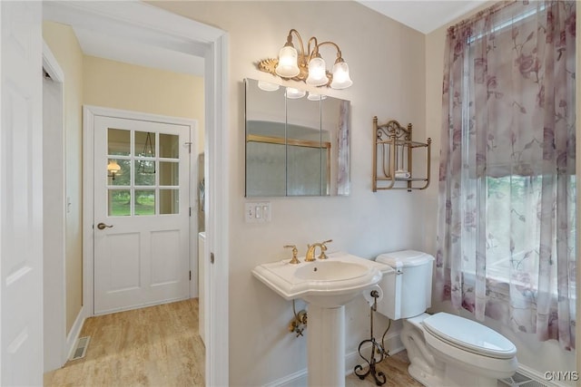 bathroom with a chandelier, toilet, wood finished floors, and a sink