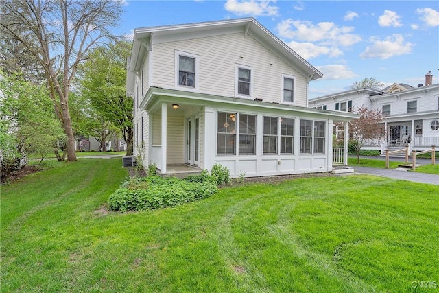 rear view of property featuring a lawn, cooling unit, and a sunroom