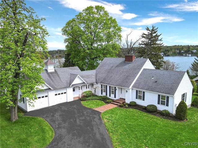 view of front of house featuring an attached garage, a front lawn, a chimney, and asphalt driveway
