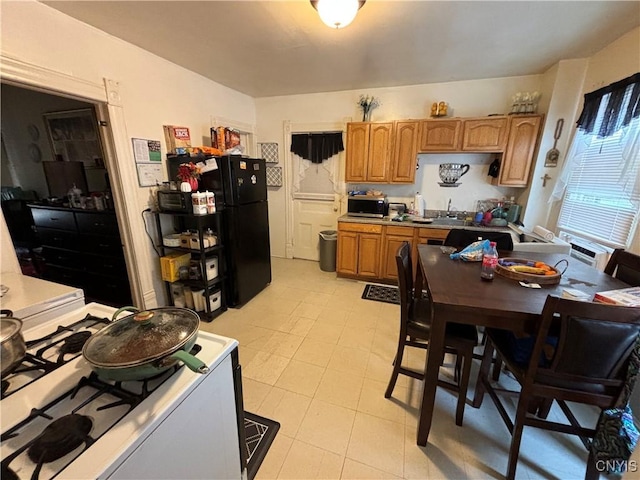 139 Pulaski St, Syracuse, NY 13204 - kitchen with gas stove, stainless steel microwave, freestanding refrigerator, brown cabinets, and a sink