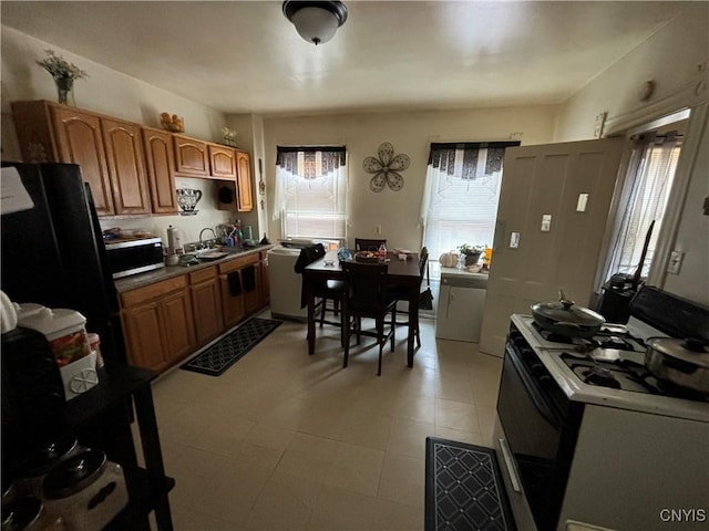 139 Pulaski St, Syracuse, NY 13204 - kitchen with stainless steel microwave, gas range oven, a sink, brown cabinetry, and freestanding refrigerator
