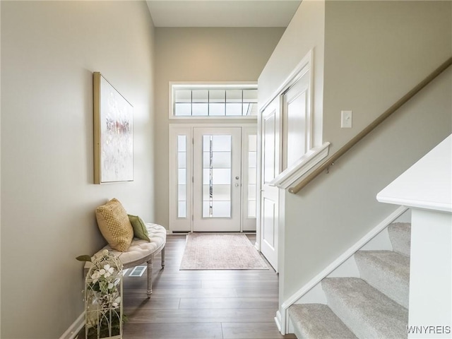 foyer entrance featuring stairs, wood finished floors, and a towering ceiling