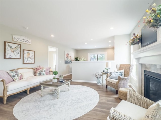 living area featuring wood finished floors, baseboards, a tile fireplace, and recessed lighting