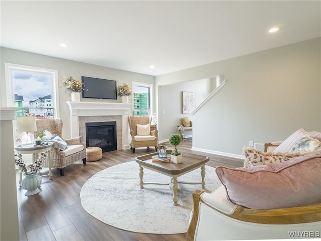 living area with a tiled fireplace, wood finished floors, baseboards, and recessed lighting