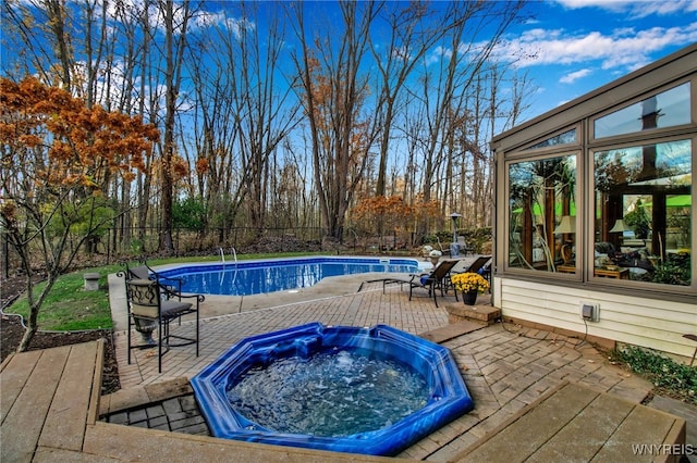 swimming pool featuring fence, an outdoor hot tub, and a patio