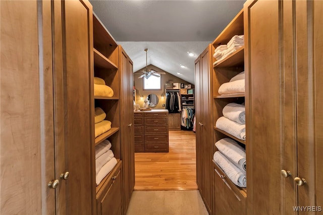 spacious closet with vaulted ceiling, light wood-type flooring, and ceiling fan
