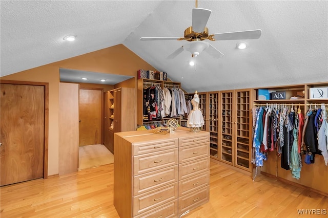 walk in closet with light wood finished floors, lofted ceiling, and a ceiling fan