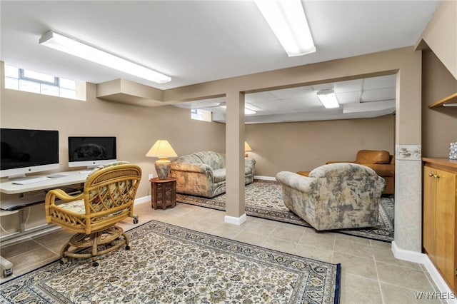 office area with light tile patterned floors, baseboards, and a drop ceiling