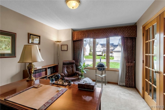 home office with light colored carpet, baseboards, and a textured ceiling