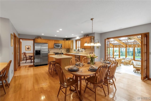 dining space with healthy amount of natural light, light wood-style floors, recessed lighting, and baseboards