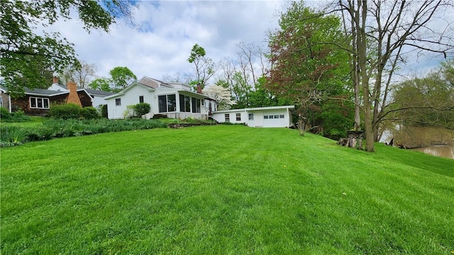 view of grassy yard featuring a sunroom and a garage