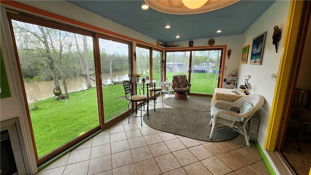 sunroom featuring a water view, tile patterned floors, and recessed lighting
