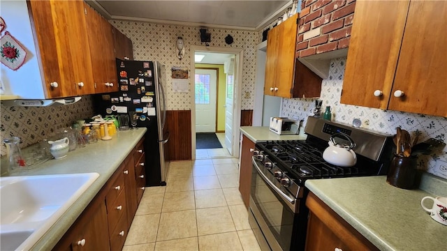 kitchen with stainless steel appliances, wallpapered walls, light countertops, brown cabinetry, and crown molding