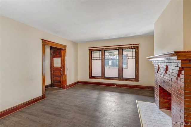 unfurnished living room with wood finished floors, baseboards, and a brick fireplace