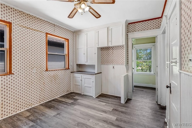 clothes washing area featuring a ceiling fan, wallpapered walls, dark wood-type flooring, crown molding, and baseboards