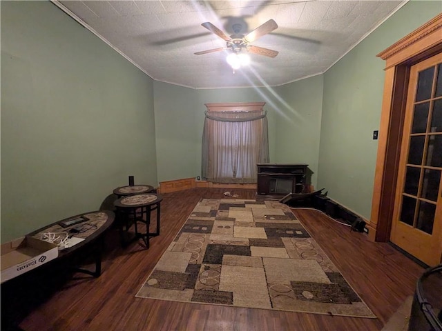 living room featuring ornamental molding, a ceiling fan, wood finished floors, and a wood stove