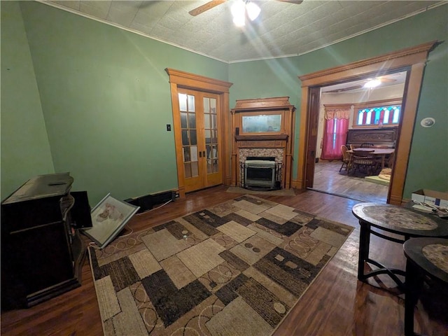 living room with wood finished floors, a ceiling fan, crown molding, and a fireplace
