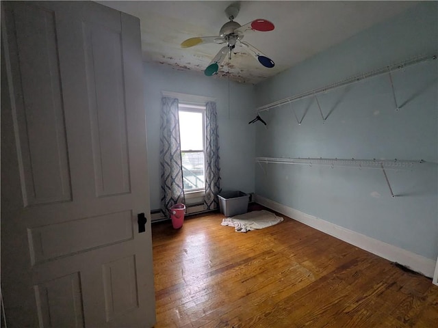 unfurnished bedroom with light wood-style flooring, a ceiling fan, and baseboards