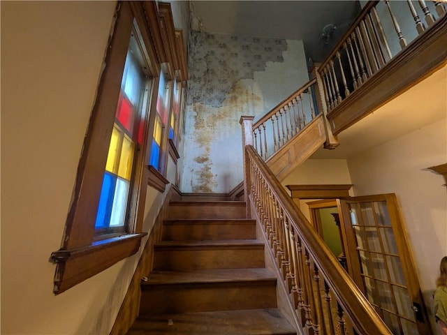 stairs with a high ceiling and wood finished floors