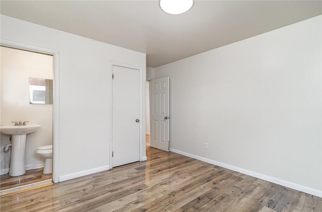 134 Schum Ln, Rochester, NY 14609 - unfurnished bedroom with wood finished floors, baseboards, a sink, and connected bathroom