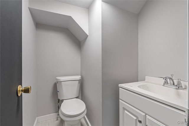 bathroom with toilet, vanity, and baseboards