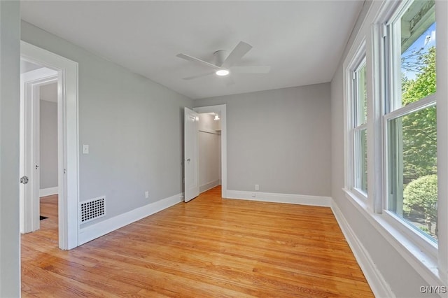empty room featuring light wood-style flooring, a ceiling fan, and baseboards