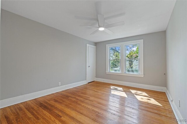 spare room featuring baseboards, light wood finished floors, and a ceiling fan