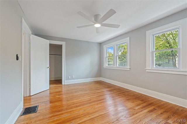 unfurnished bedroom with light wood finished floors, baseboards, and a spacious closet