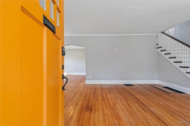 unfurnished living room with ornamental molding, wood finished floors, stairs, and baseboards